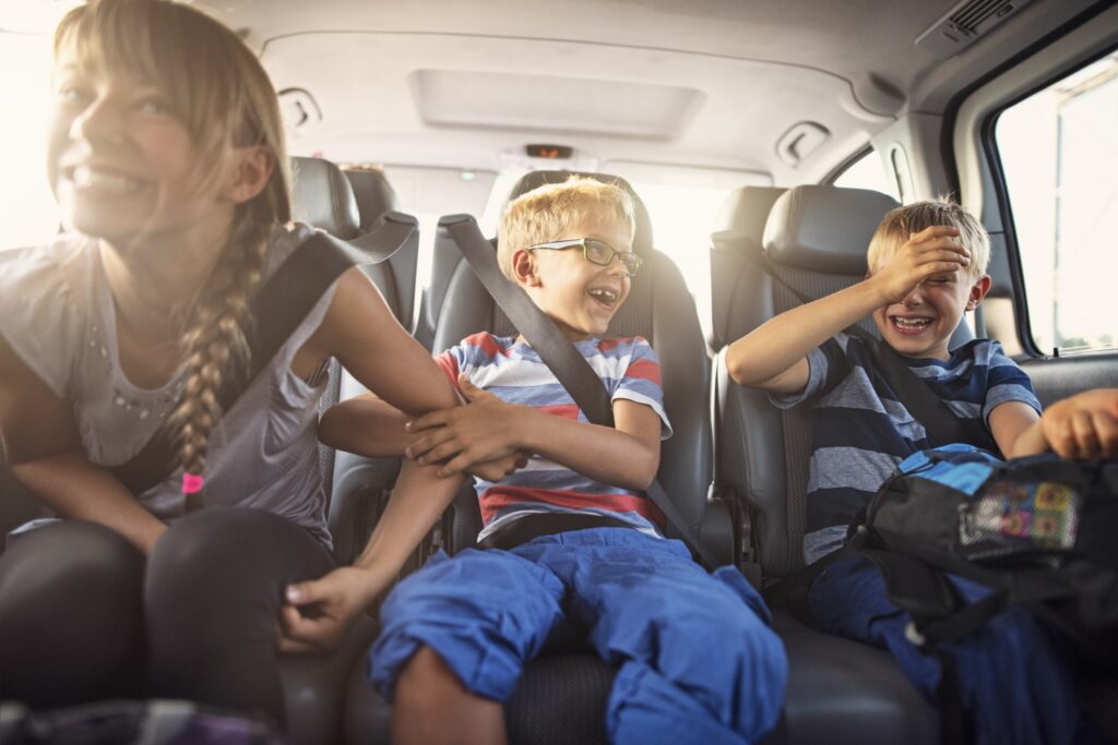 Happy playful kids travelling by car